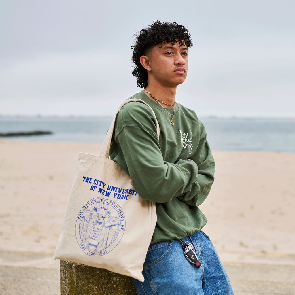 Person holding a tote bag with a visible logo on a beach